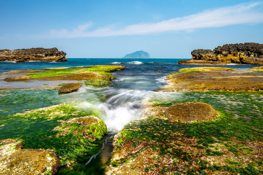 石頭覆蓋上一整片亮綠色的海藻，稱為“綠寶石祕境”